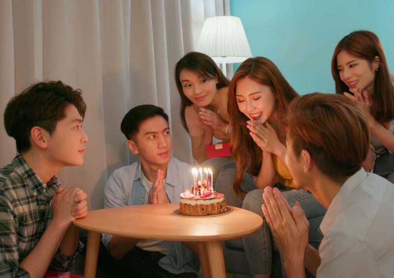 Group of people gathered around a birthday cak