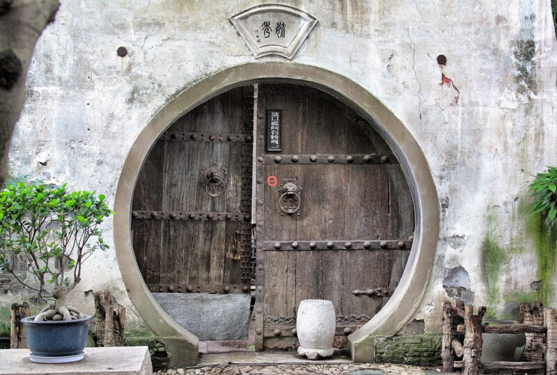 Photo of a round, closed wooden door to an ancient Chinese house