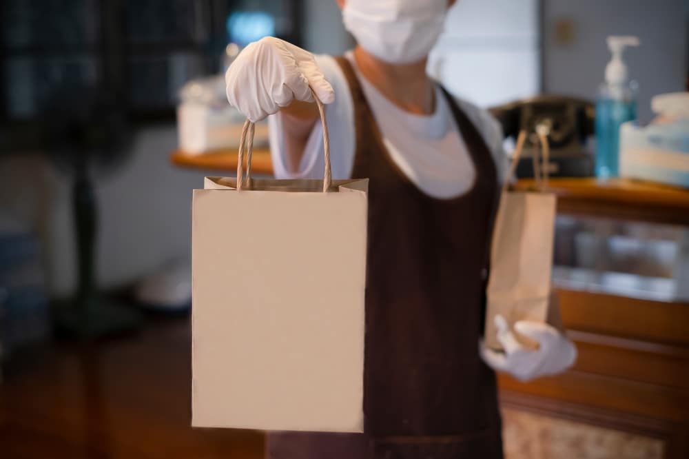 asian woman handing over a delivery food bag in a restaurant