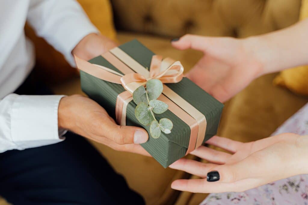 people giving and receiving green gift box with both hands
