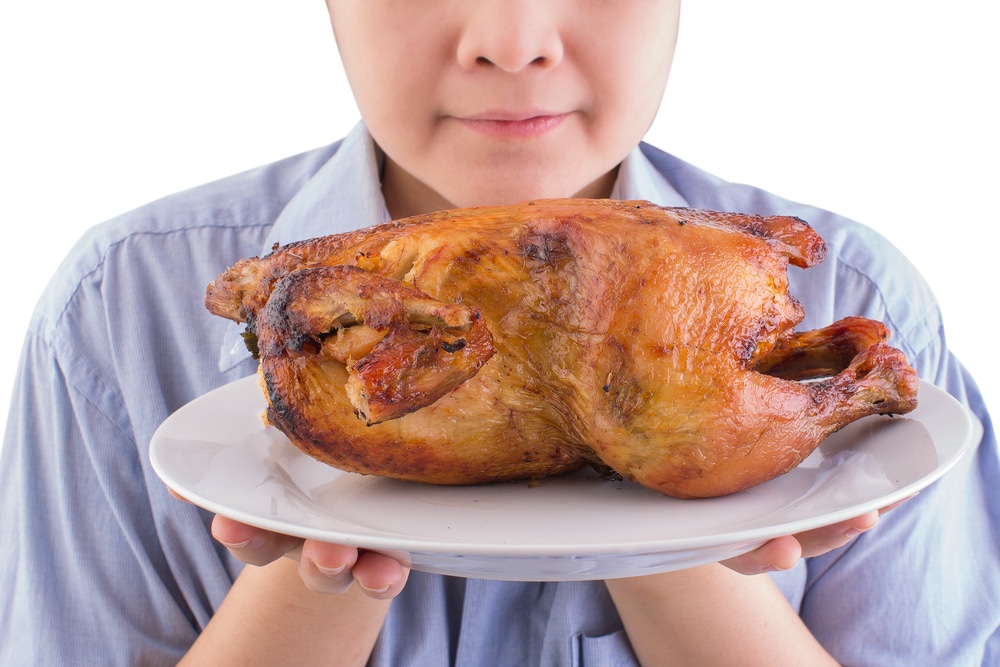 man smelling a roast chicken on white background