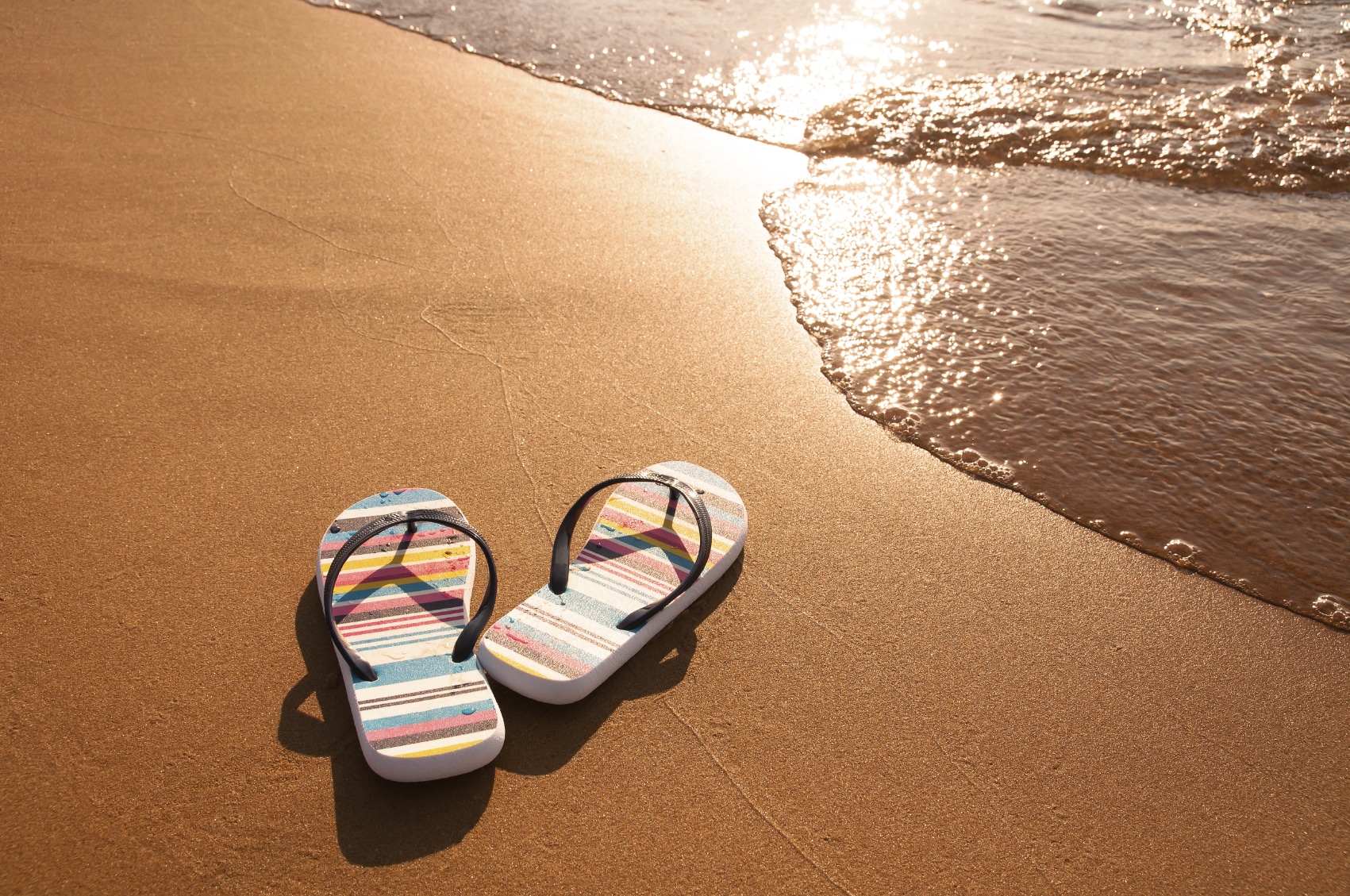 colorful sandals on the sand near the ocean