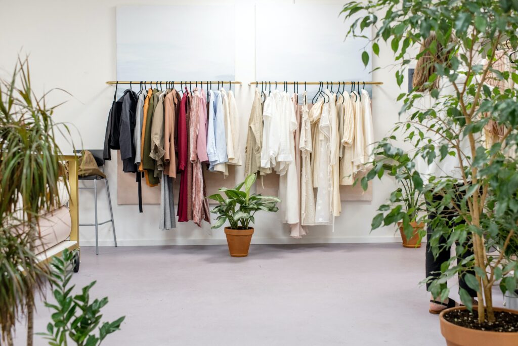 clothes hanging on rack with potted plants nearby
