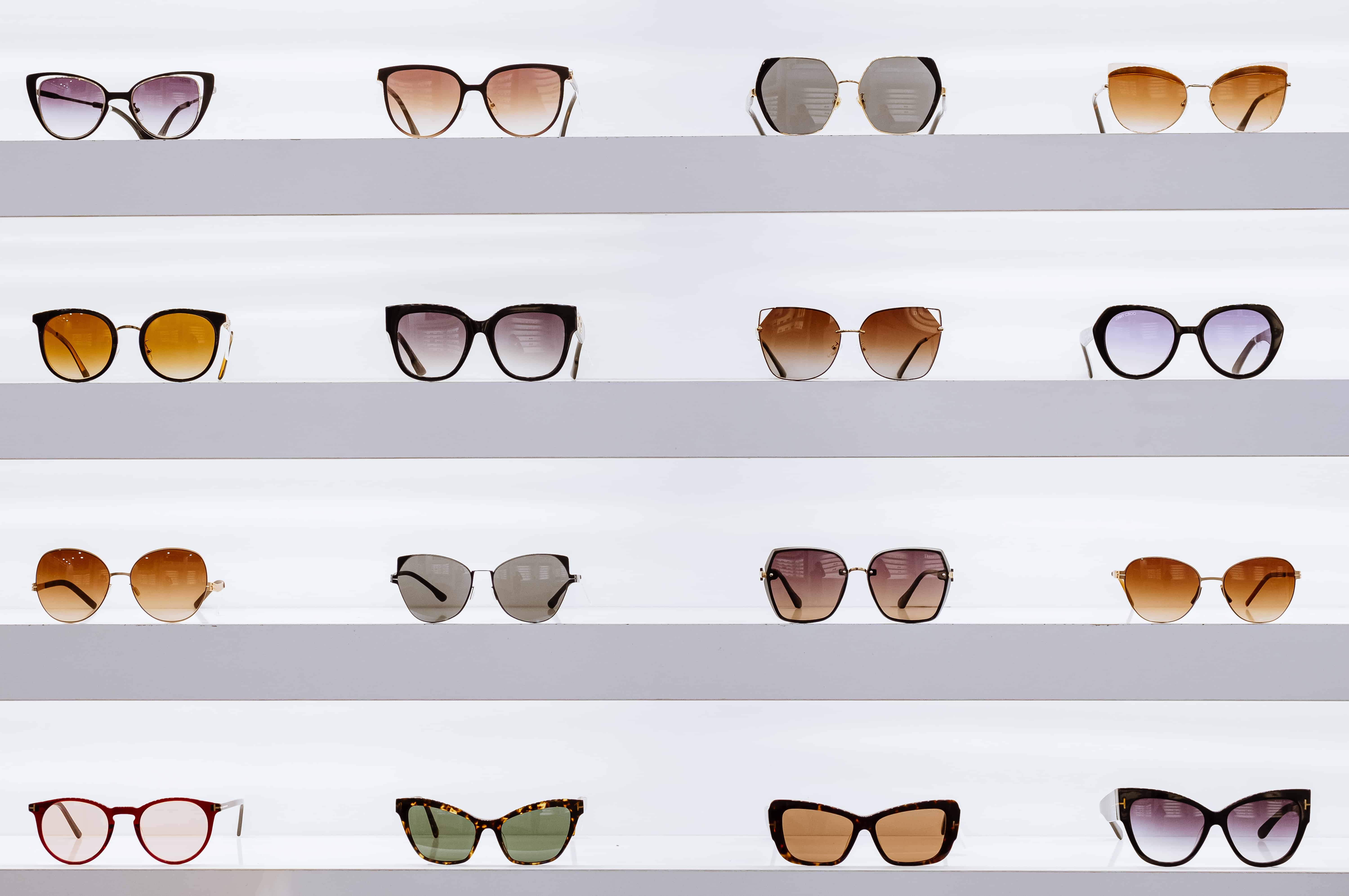 sunglasses of different shapes and colors on store wall