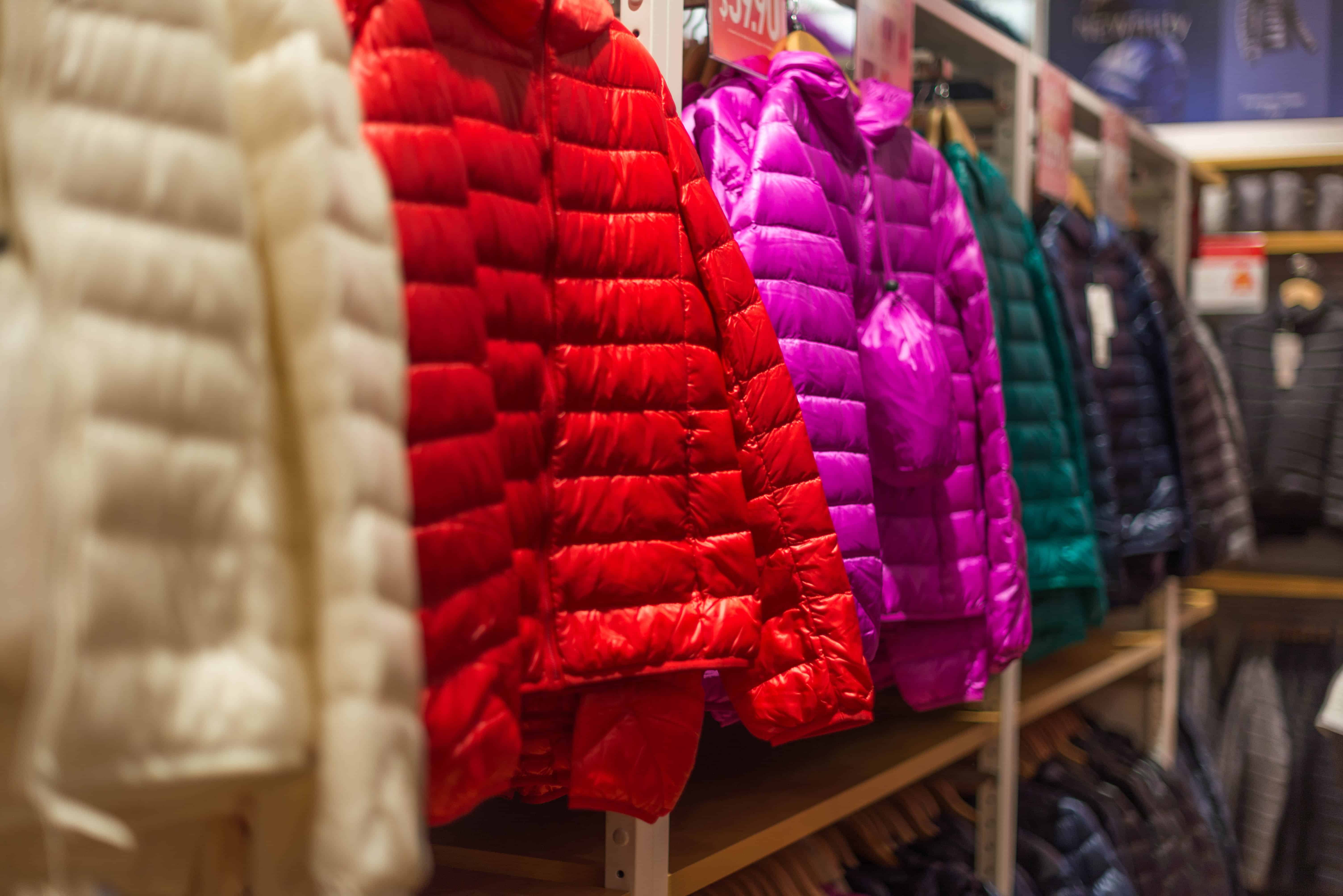 puffy winter jackets in bright colors hanging in store