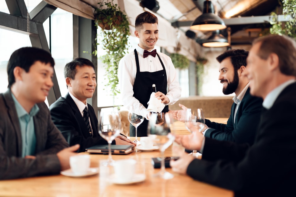 The-waiter-brought-good-wine-for-business-people-in-a-restaurant.-Business-people-sitting-at-a-table-in-a-restaurant-and-discussing-business