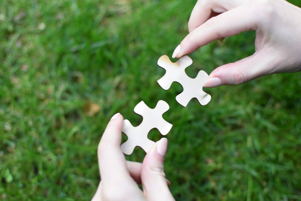 Person Outside Linking Two White Puzzle Pieces Together