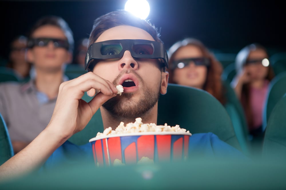 guy watching movie in theater while wearing 3d glasses