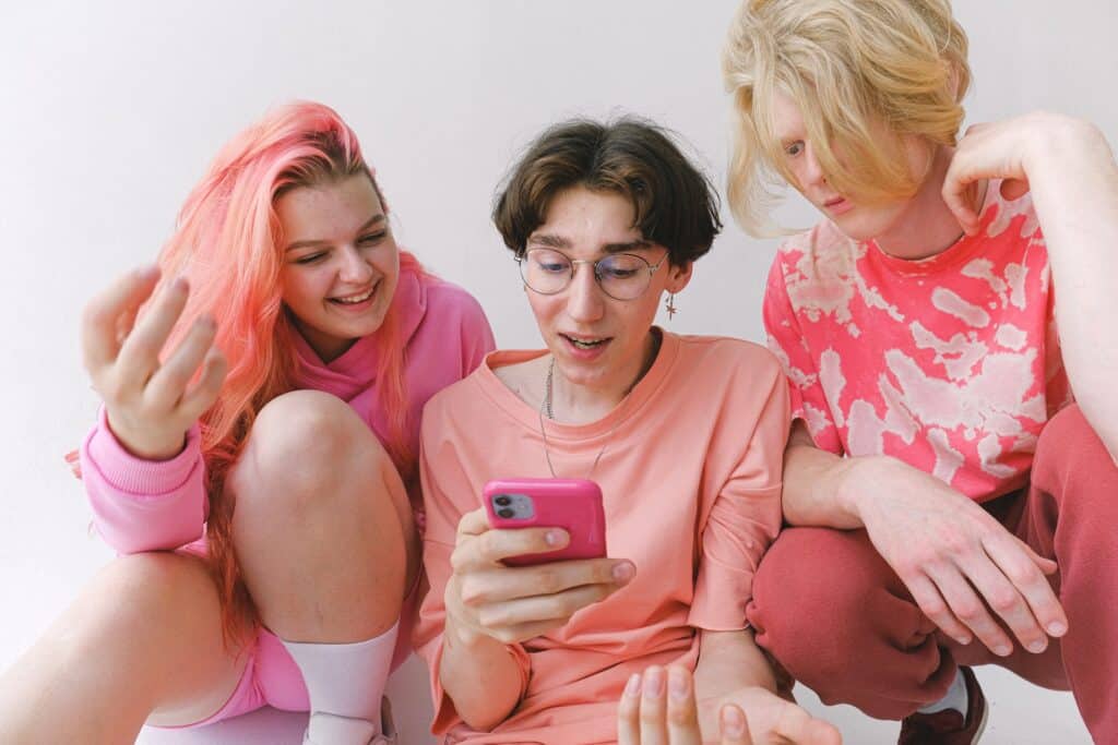 three-young-people-in-pink-looking-at-the-middle-person's-phone