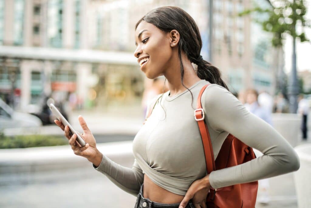 shallow-focus-photo-of-woman-smiling-as-she-holds-her-smartphone
