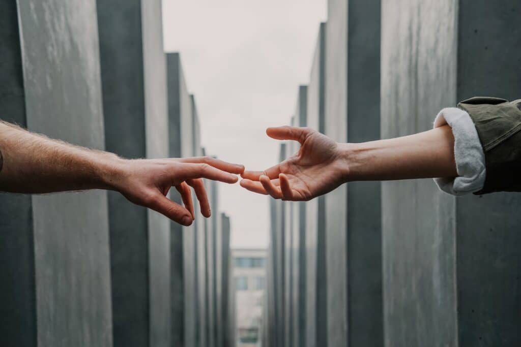 Two Hands Reaching For Each Other Across Gray Buildings