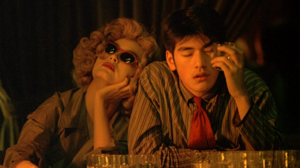 A man and woman sit at a bar in this still from Chungking Express
