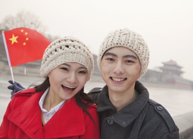 portrait of young couple holding Chinese flag outdoors in wintertime