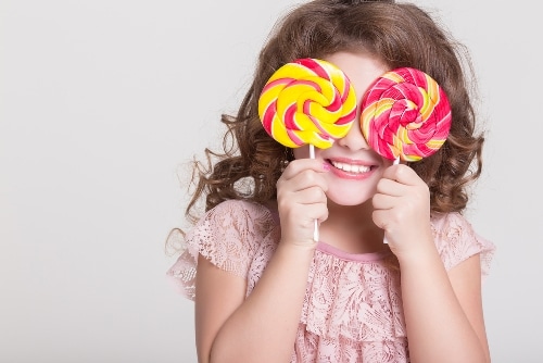 Girl holding two lollipops over her eyes