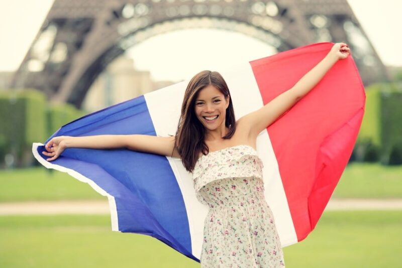 woman-standing-in-front-of-the-eiffel-tower-in-paris-holding-a-french-flag