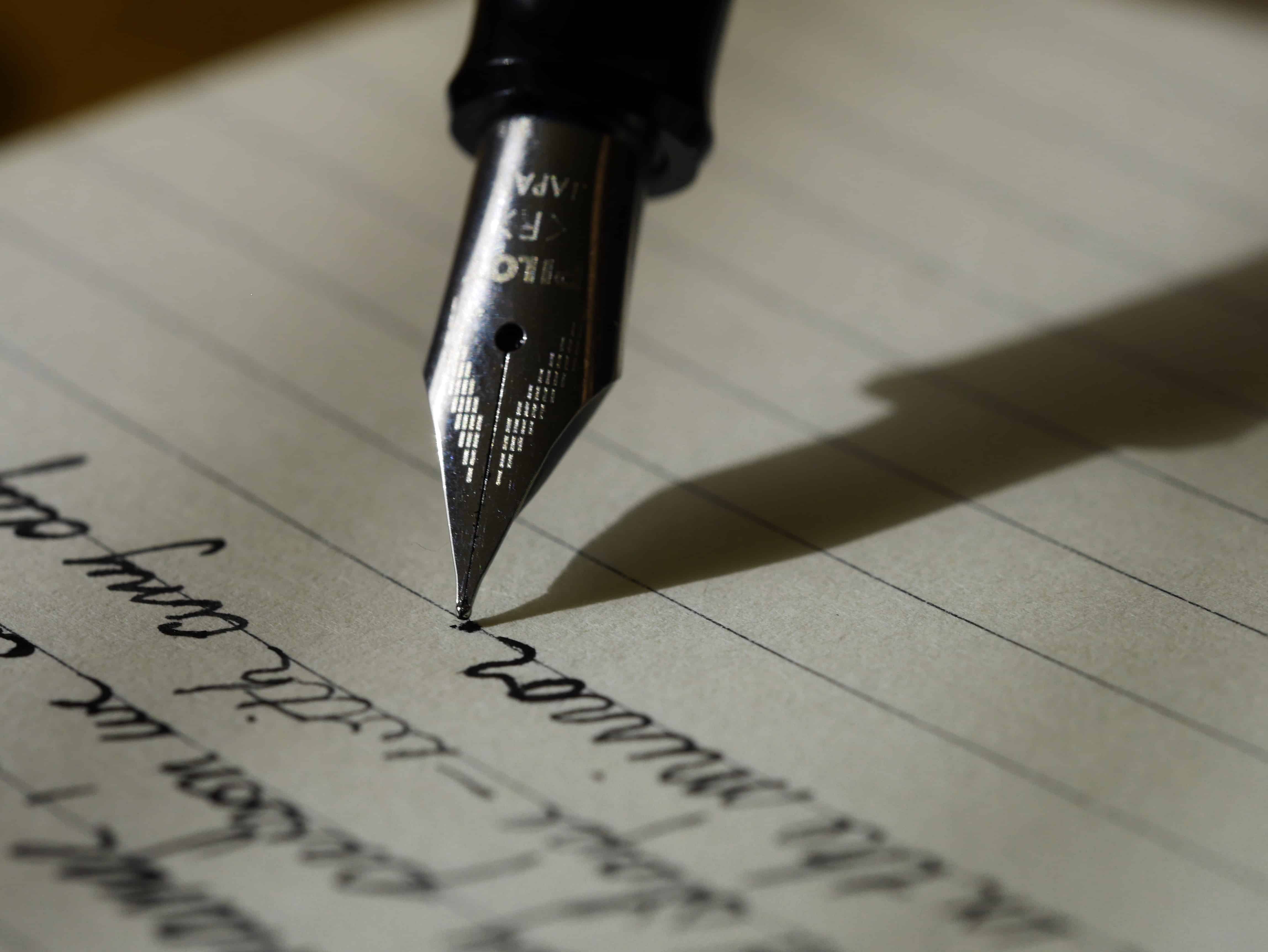 A person writing with a fountain pen on paper