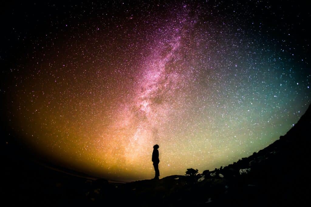 A person stands beneath a starry night sky