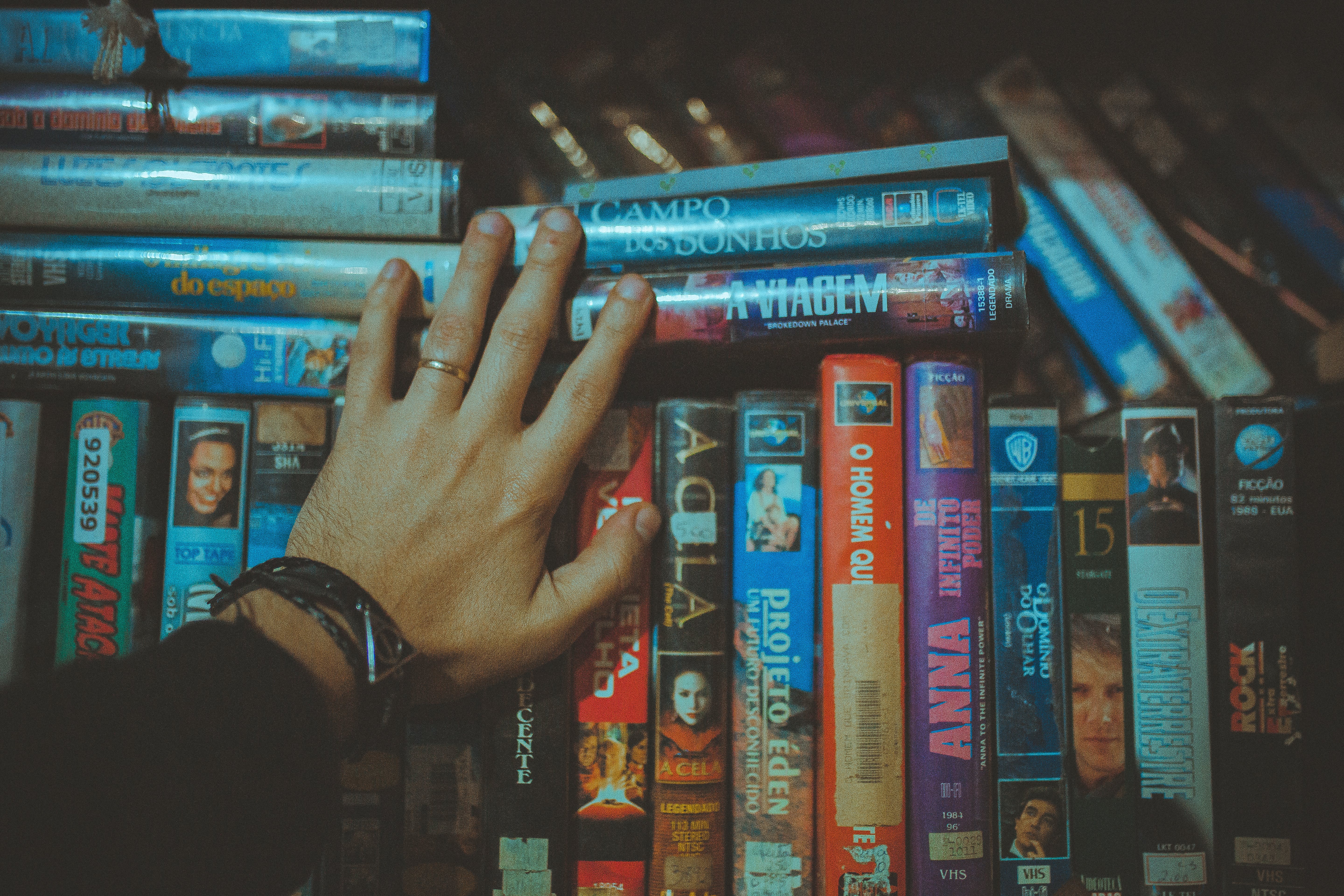 A hand searches fora  movie on a shelf of DVDs