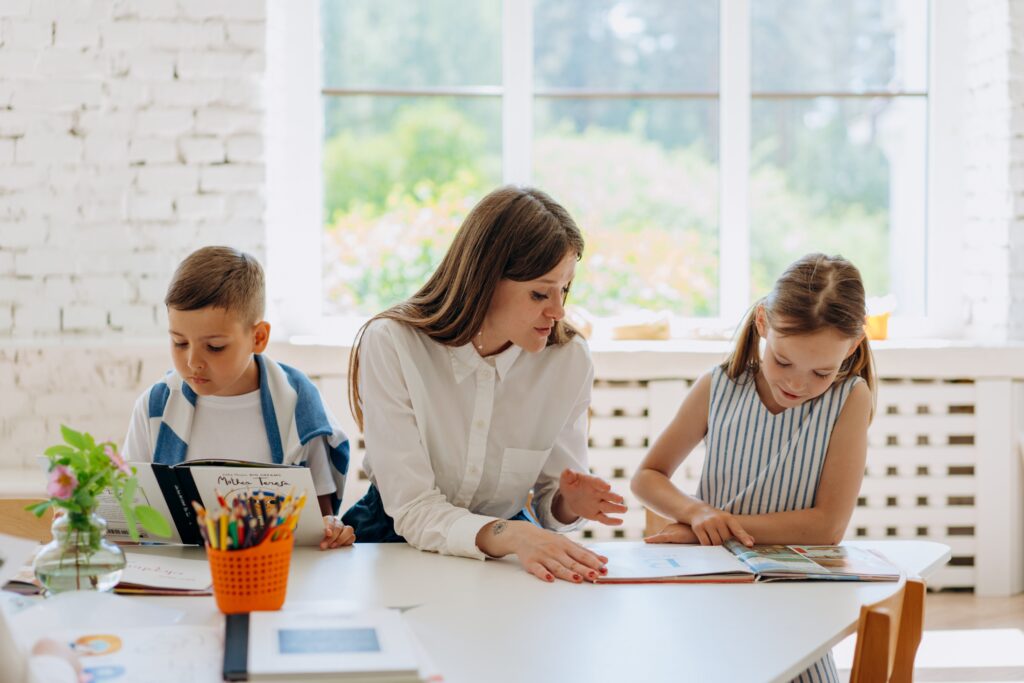 A teacher works with two students at a table