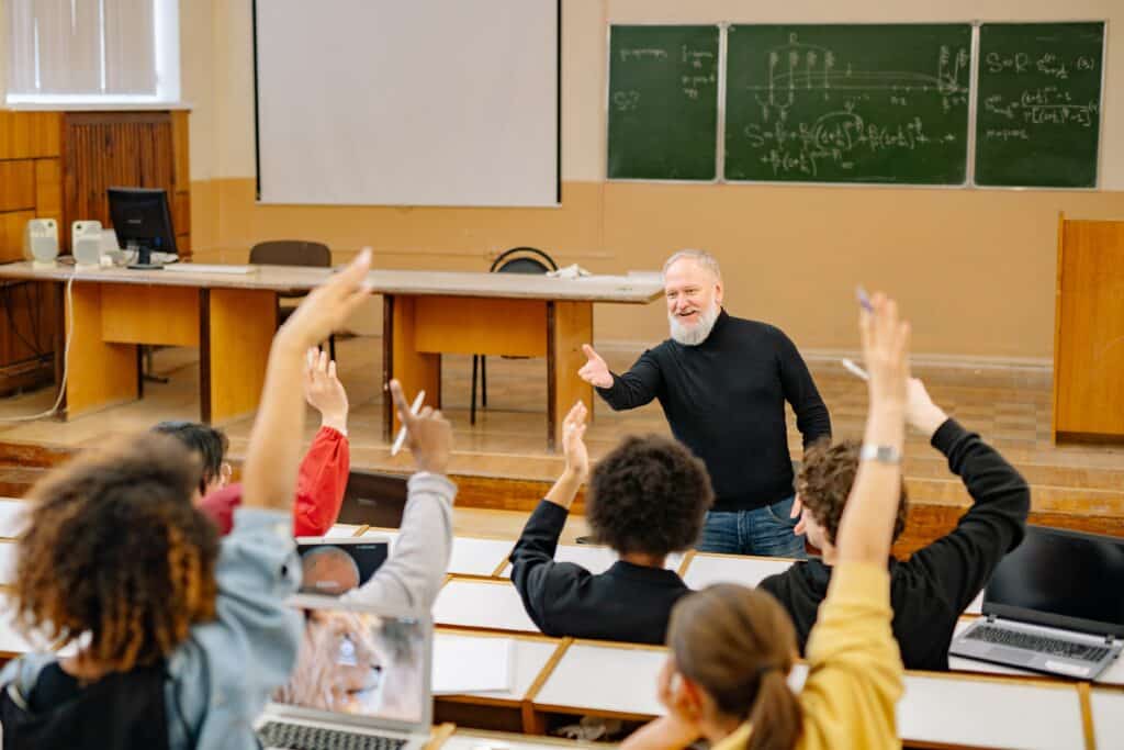 students-raising-their-hands-in-lecture-hall-while-lecturer-teaches