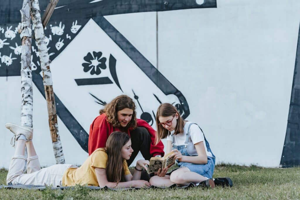 group-of-teenagers-young-people-reading-a-book-in-the-grass