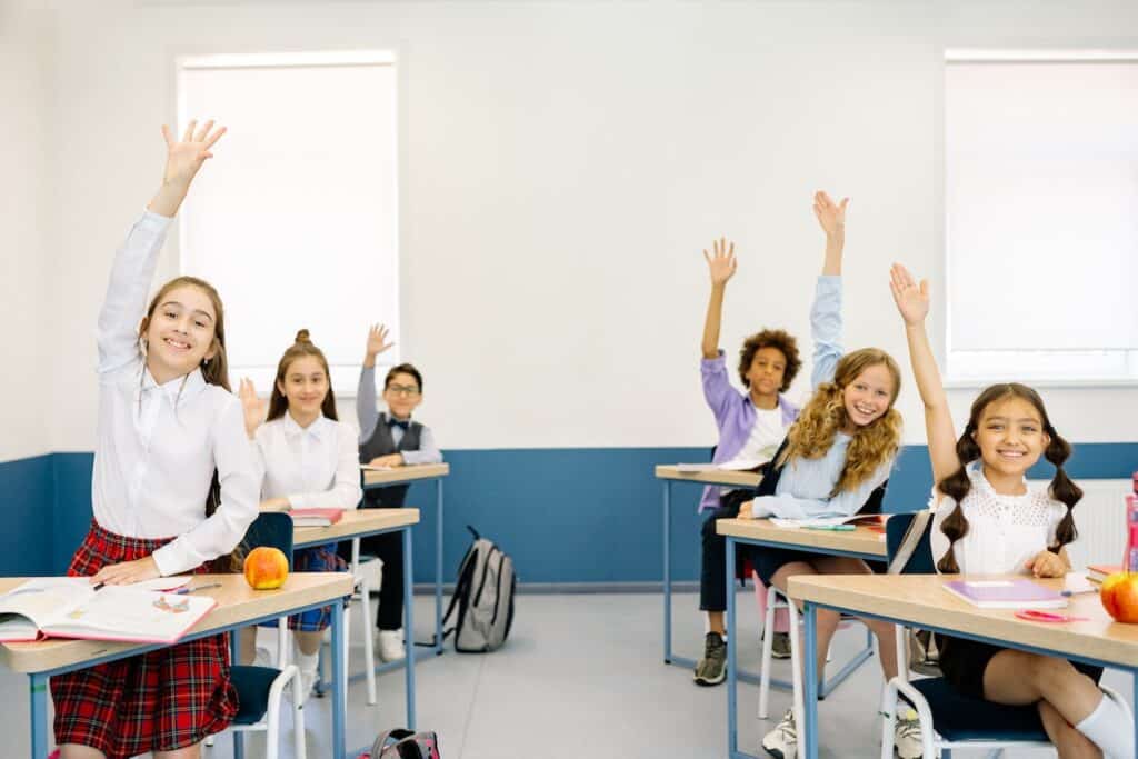 students raising their hands in class