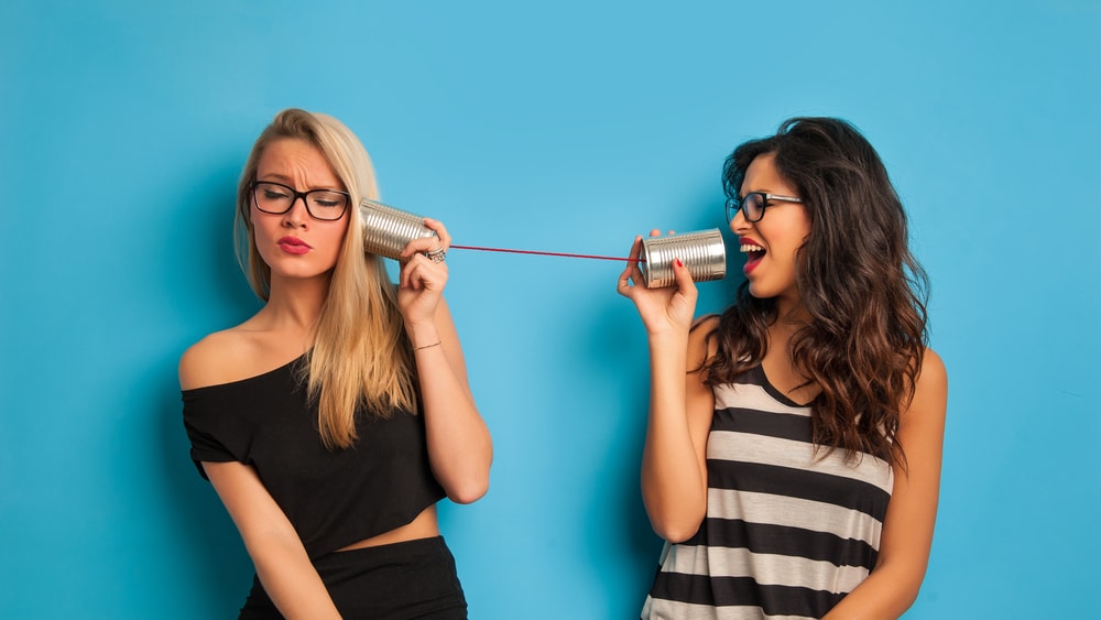 women talking with tin can telephone
