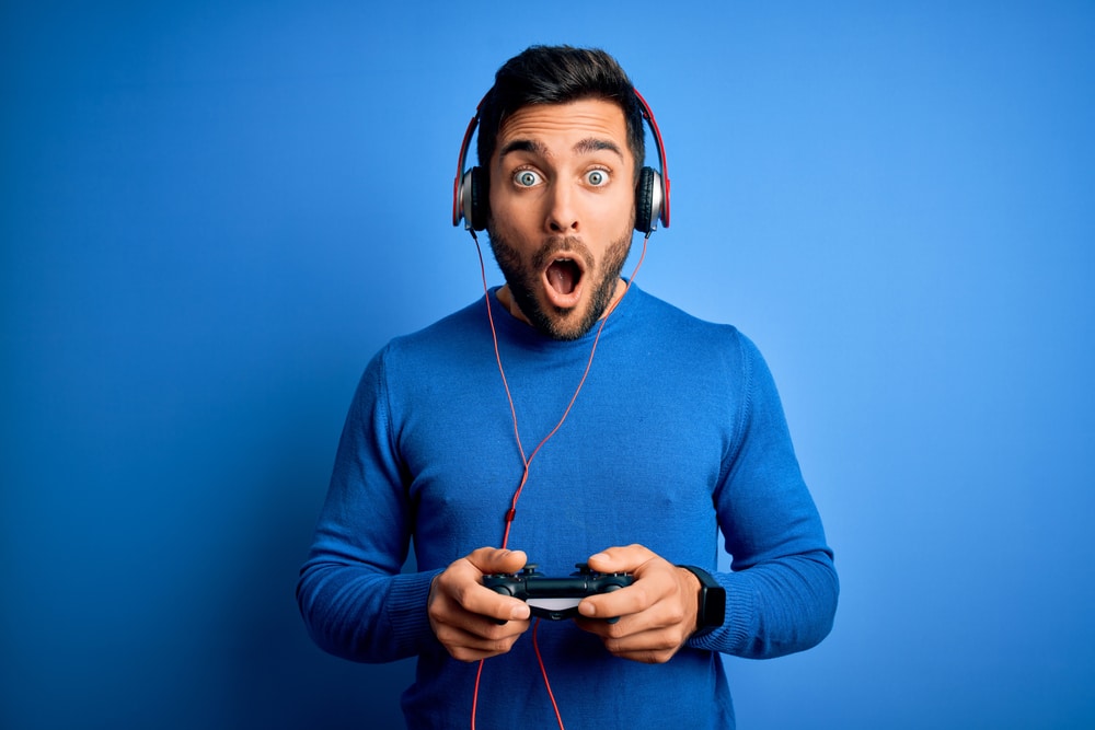 Young handsome gamer man with beard playing video game