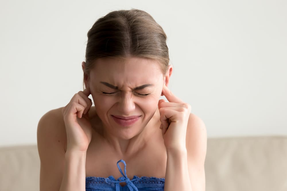 Young annoyed woman sticking fingers in ears