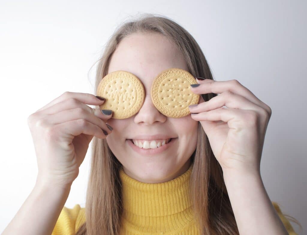 girl smiling with cookies over her eyes.