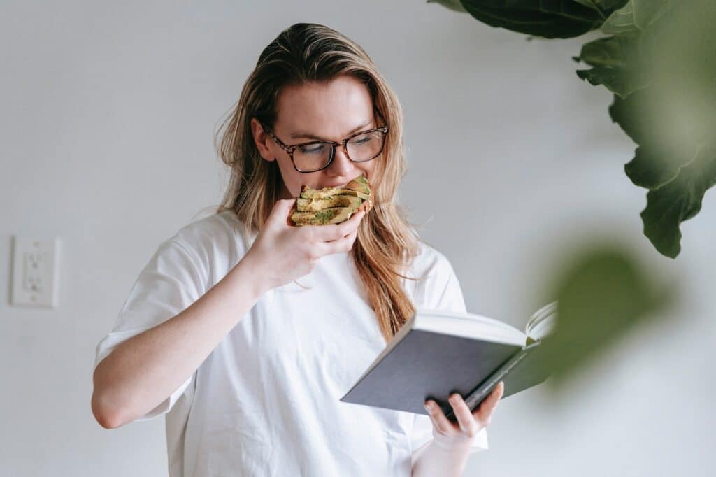 Girl eating a bite while reading a book