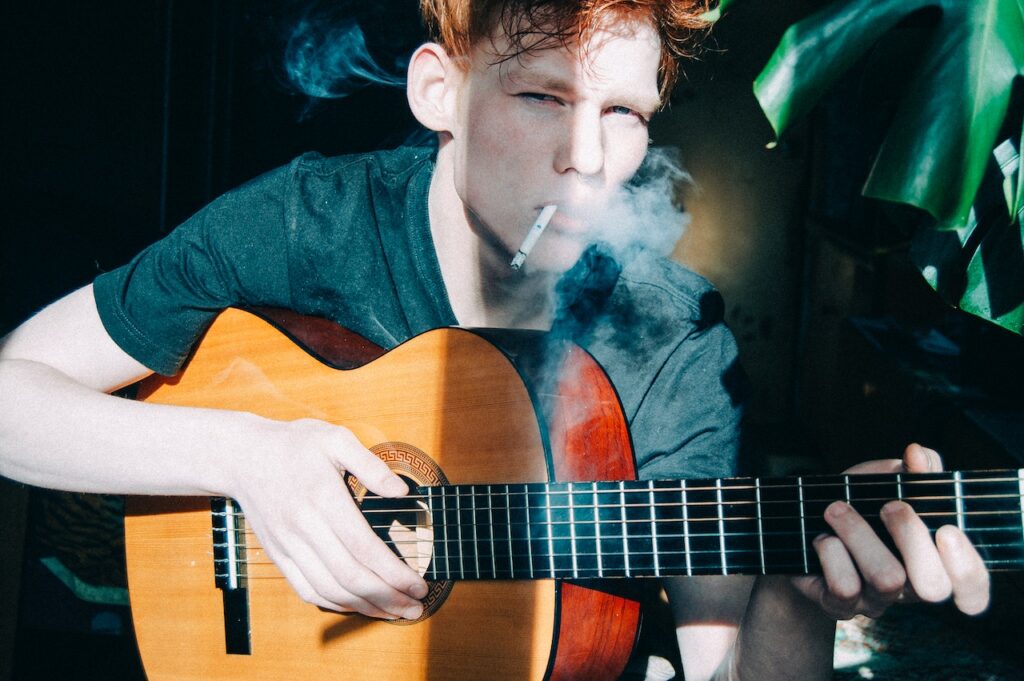 Boy playing guitar and smoking