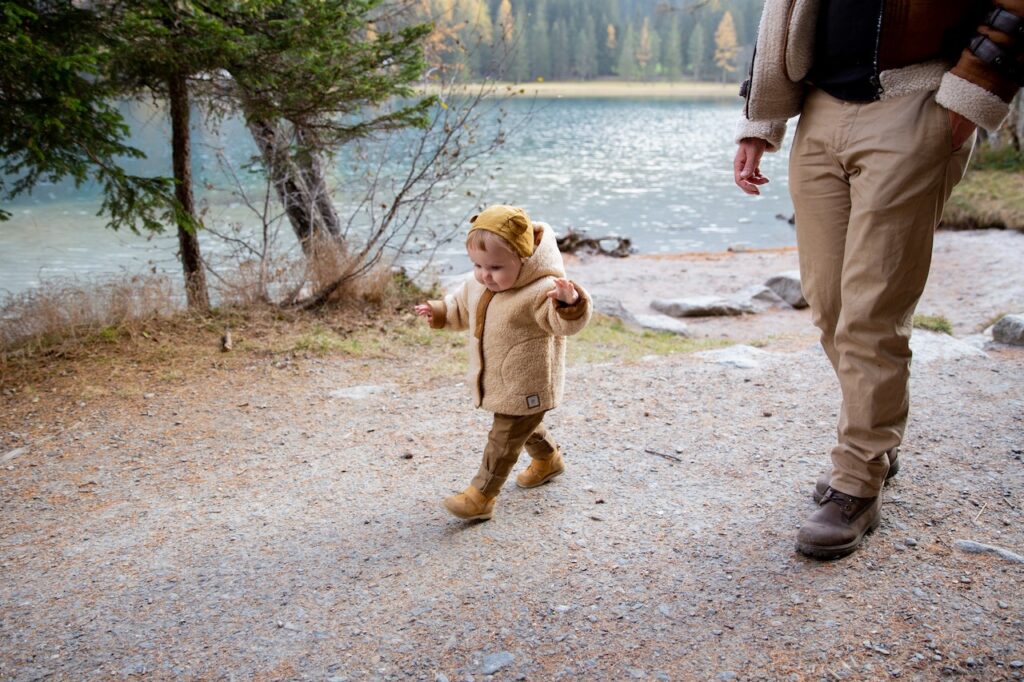 baby walking along his father