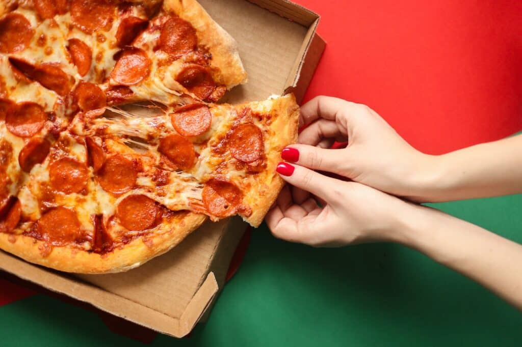 Hands taking a slice of pizza