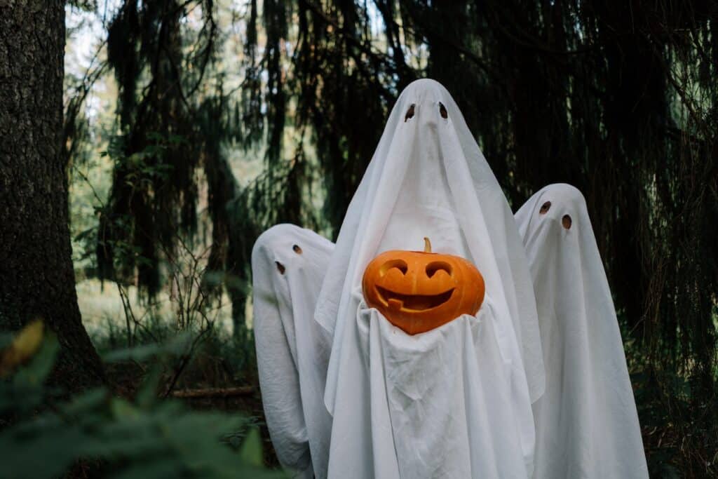 Three ghosts holding a pumpkin