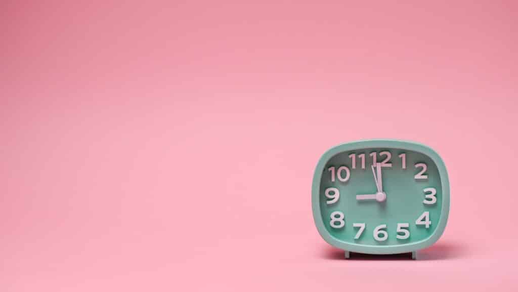 Small clock over pink background