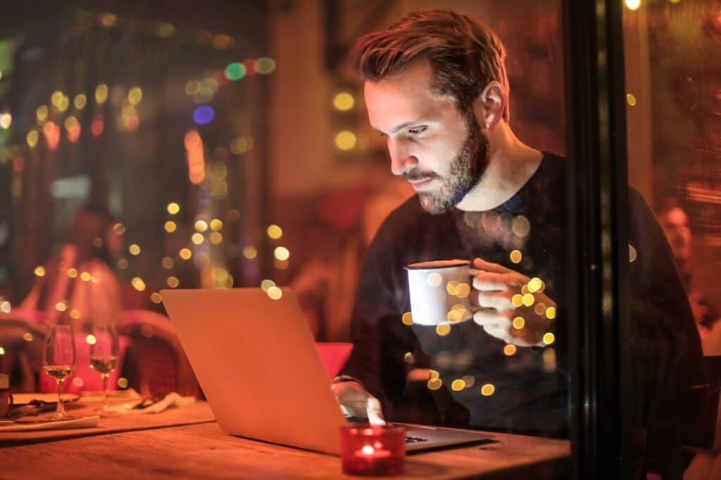 A man having a coffee while using laptop