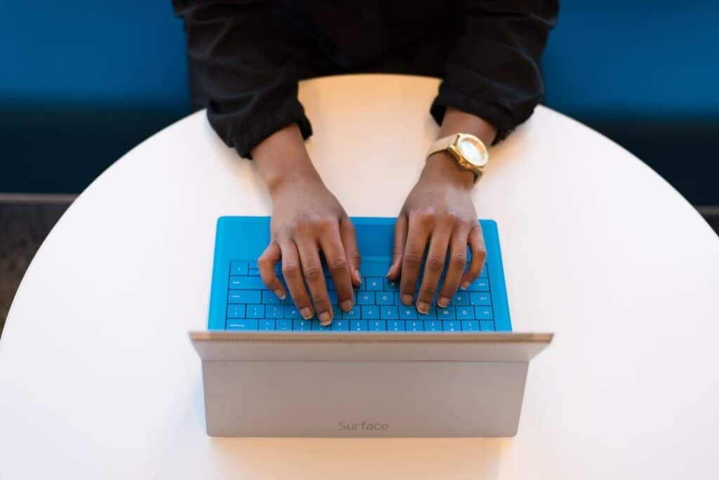 A person typing on a blue laptop