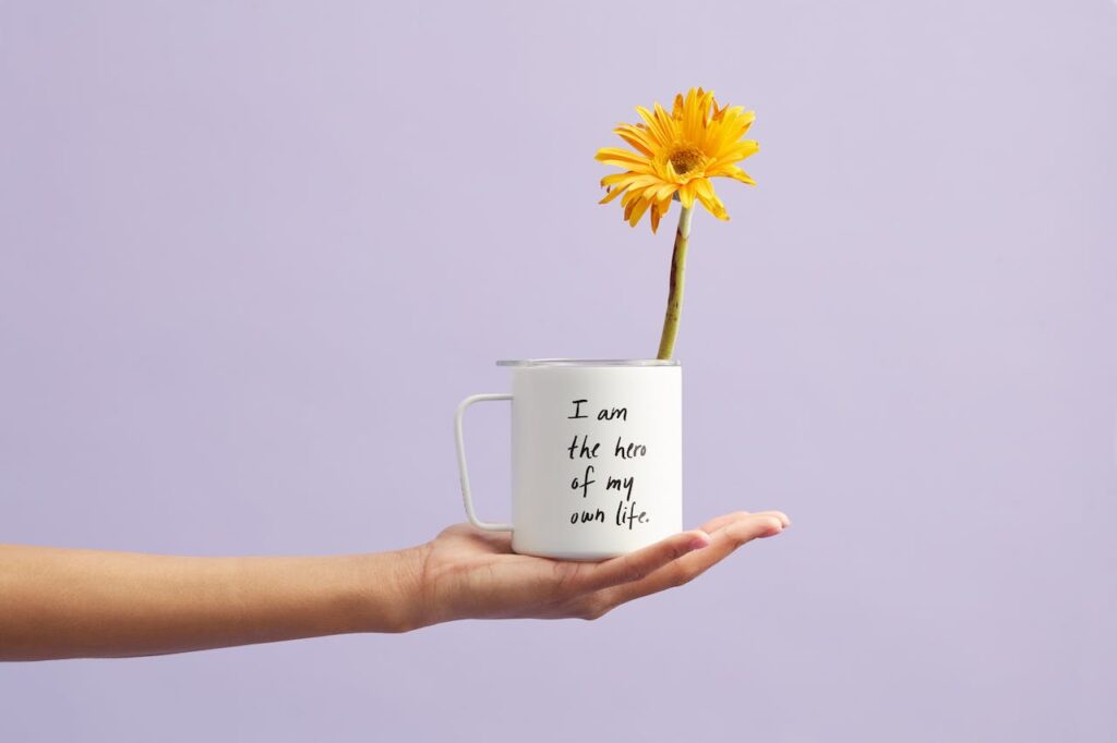 A hand holding a cup with a motivational quote