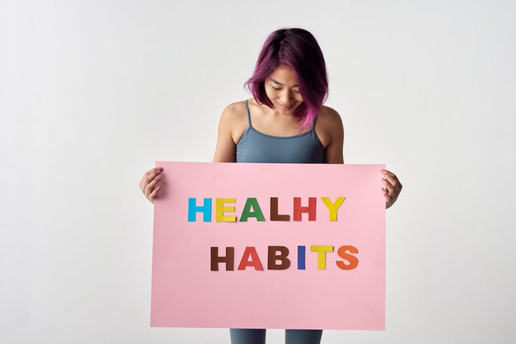 A woman holding a sign with "Healthy habits" written on it.