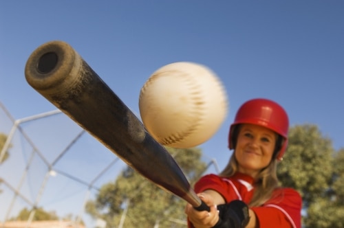 Woman hitting a baseball with a bat.
