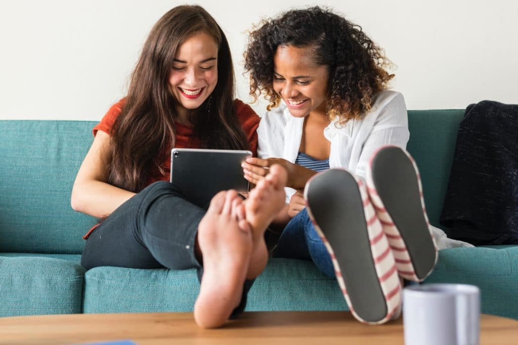 Two women looking at a tablet while sitting on a sofa