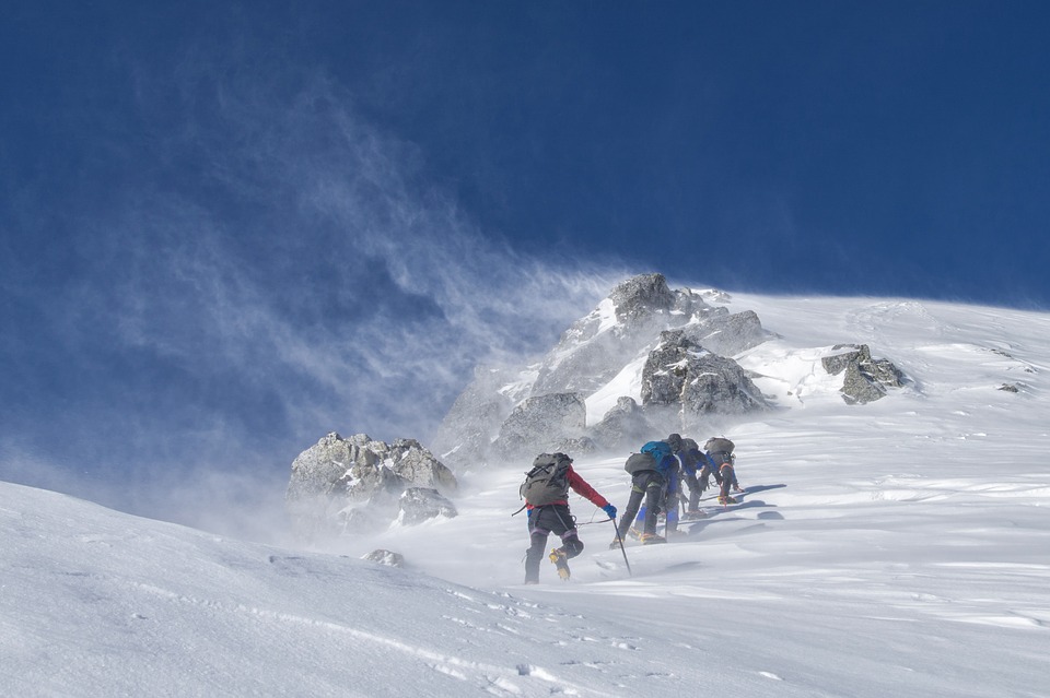 group-of-people-climbing-up-a-snowy-mountain-with-low-cloud