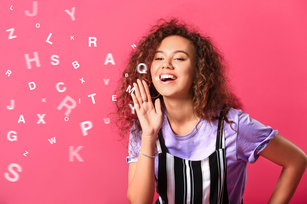 Women breathing out different white letters on a pink background