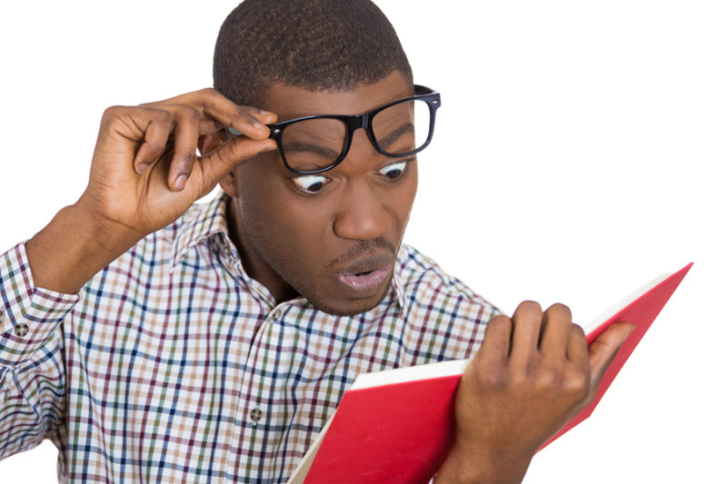 man with glasses surprised at book