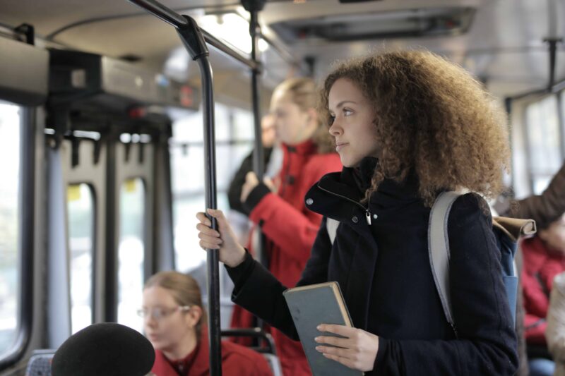 girl-inside-bus-holding-rail-and-book