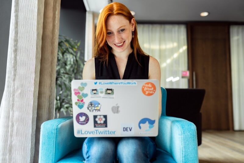red-haired-woman-on-a-laptop-with-a-lot-of-stickers-on-it