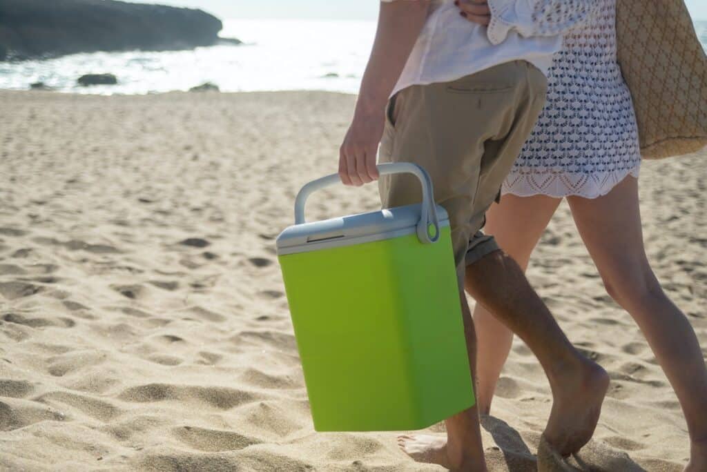 couple carrying a beach cooler