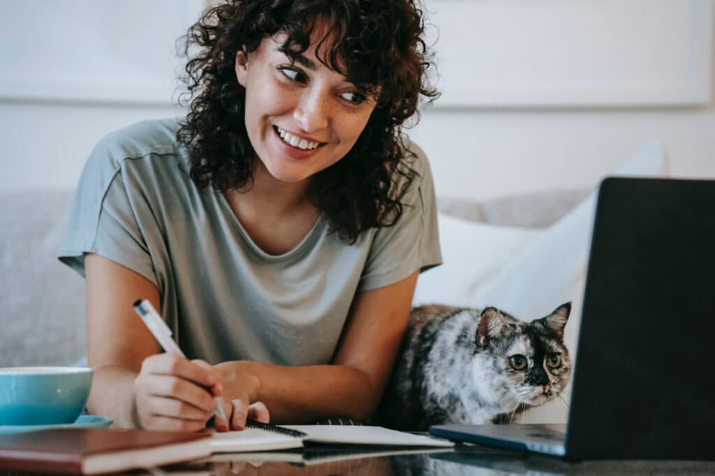 Woman and cat look at laptop screen