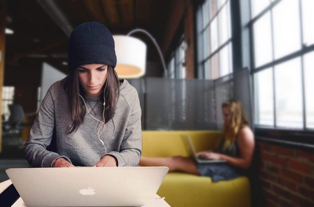 young-woman-with-earbuds-studying-on-laptop